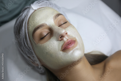Beautiful woman with mask on her face in spa salon