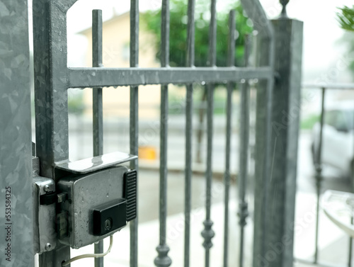 Stainless electromechanical lock on gate outdoors under rain