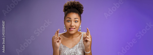 Excited african-american girl excited eager win cross fingers good luck biting lip desire anticipation making wish, eager receive gift, standing optimistic thrilled in silver dress blue background photo