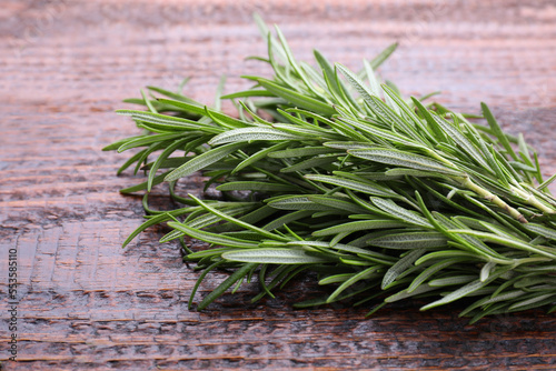 Fresh green rosemary twigs on wooden table, closeup