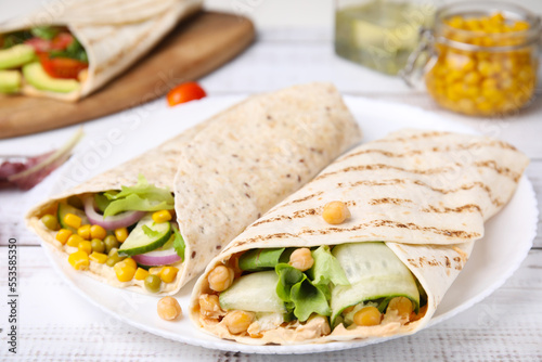 Delicious hummus wraps with vegetables on table, closeup