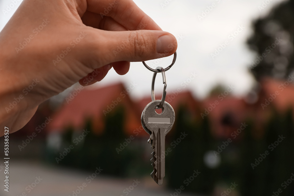Real estate agent holding keys to new house outdoors, closeup Real estate agent holding keys to new house outdoors, closeup