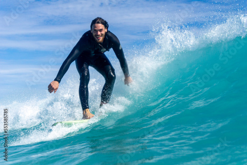 Photography In water shot of a surfer on a wave surfing and smiling at the camera
