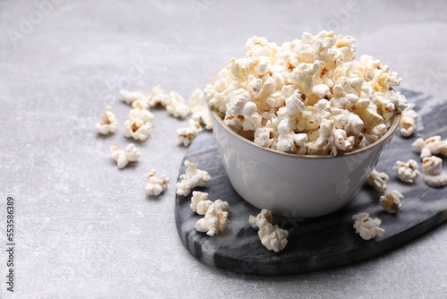 Bowl of tasty popcorn on grey table, space for text