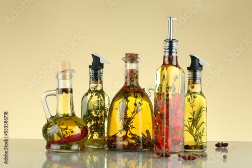 Cooking oil with different spices and herbs in bottles on beige table