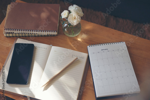 Agenda, planner book, calendar, pencil, and cup of coffee place on office desk. Diary for organizer to plan timetable, daily appointment, and management job at room. Planner book and Calendar Concept. photo