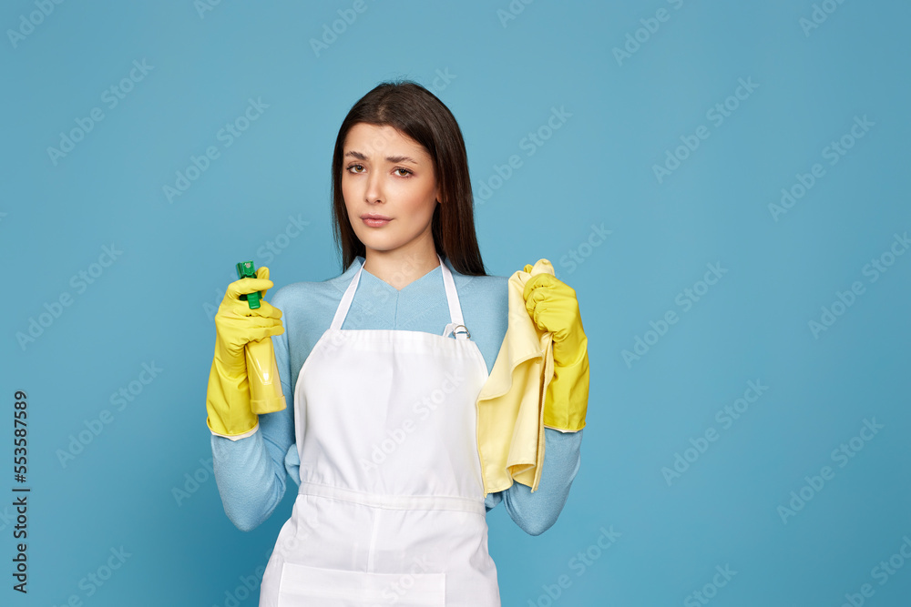 frowning woman cleaner apron with cleaning rag and detergent sprayer frowning woman cleaner apron with cleaning rag and detergent sprayer