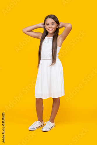 smiling teen girl in white dress standing on yellow background