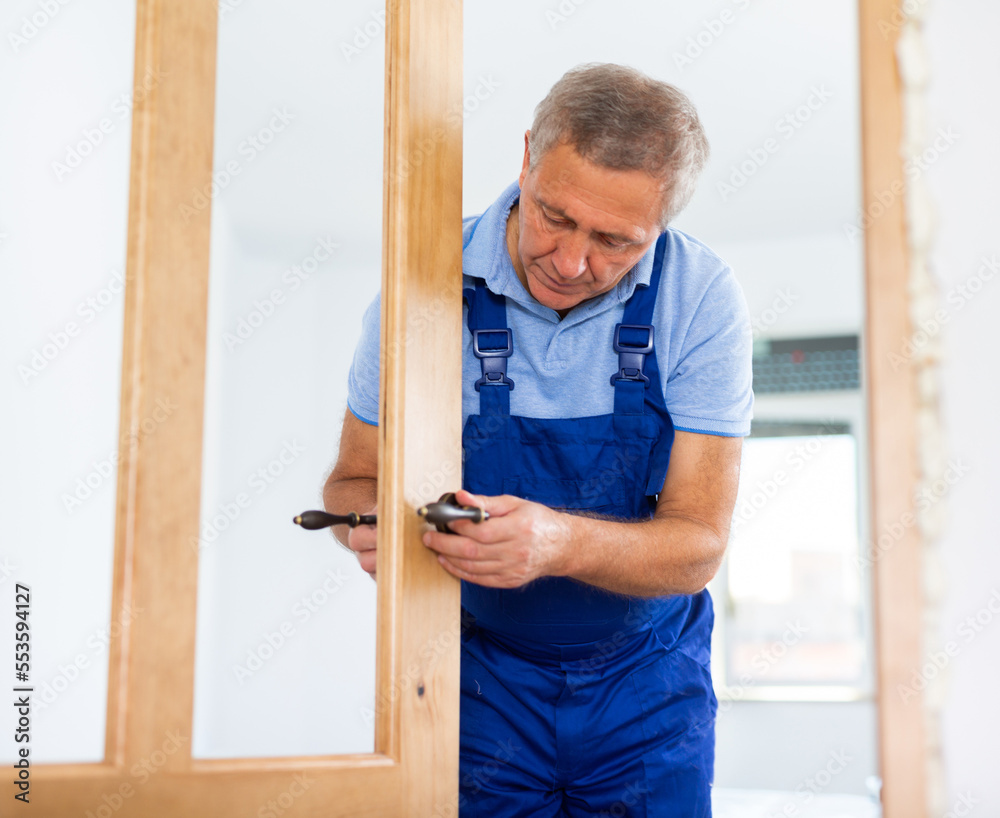 Fototapeta premium Man trying on door handles to install on a new wooden door
