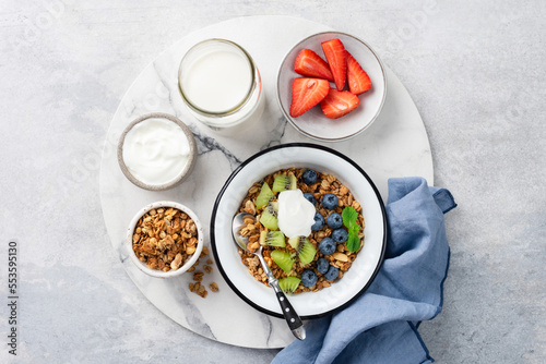 Granola with fruits and yogurt in a bowl. Table top view. Sweet breakfast cereals food