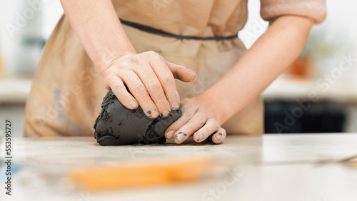 The master of sculpting pottery working in a studio. Kneading a piece of clay with her hands. Tools on the table