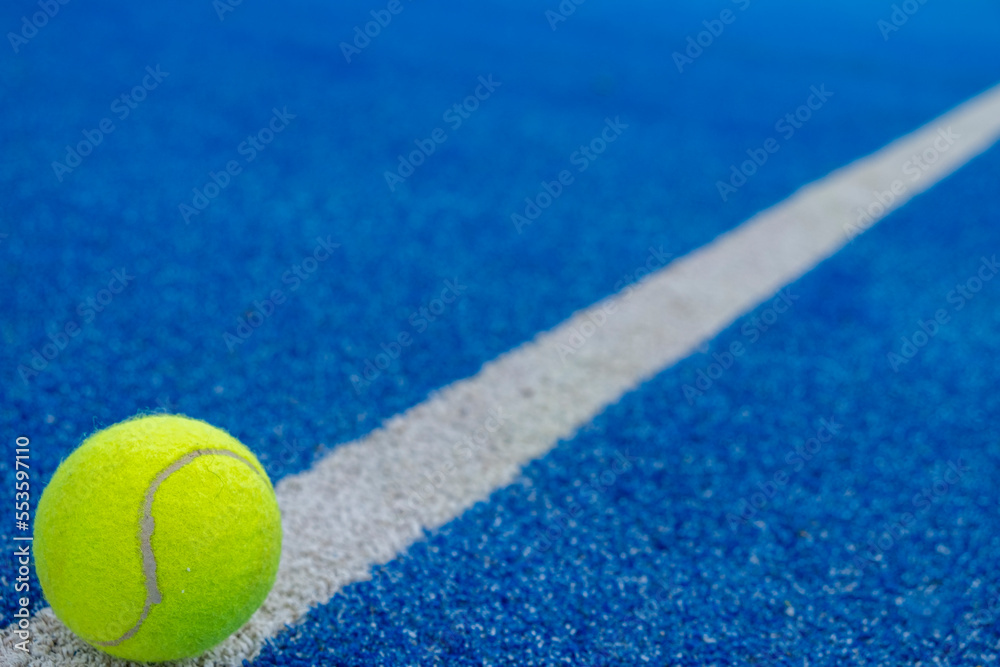 a ball on the dividing line of a blue paddle tennis court