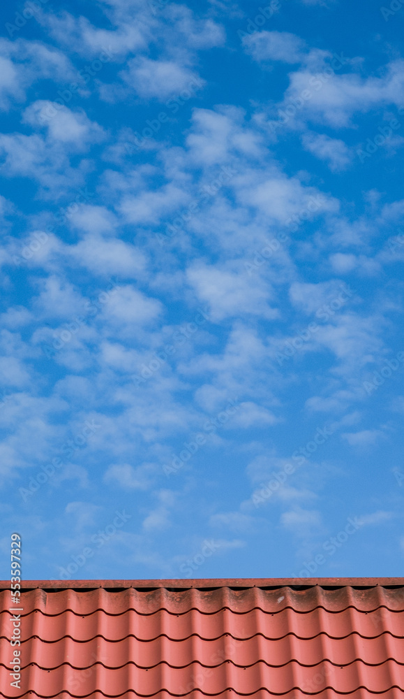 Red tiled roof. CLouds in blue sky. Close-up. Red tiled roof. CLouds in blue sky. Close-up.