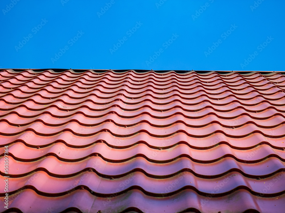 Red clay ceramic tiled roof. Blue sky. Close-up. Red clay ceramic tiled roof. Blue sky. Close-up.