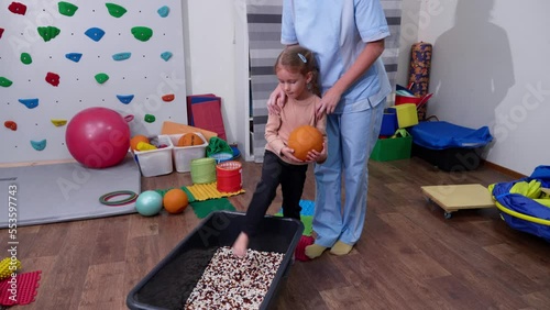 Kid on Sensory Mat Massage during sensory integration session. child girl in rehabilitation centre with physiotherapist doing orthopedic correction.  photo