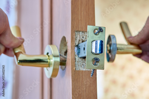 Wall Mural Locksmith is repairing faulty lever door handle with latch.
