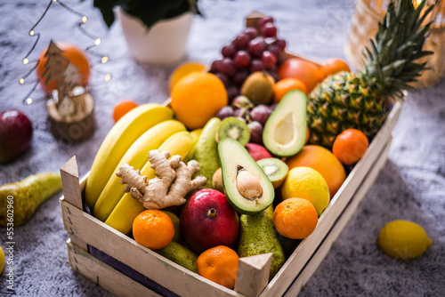 Winter healthy fruit wooden box with apples  kiwi  banana  avocado  ginger  pineapple  lemons  oranges and more ready for Christmass table.