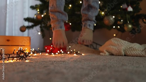 Jumping feet against the background of a decorated Christmas tree and New Year's garlands. Merry Christmas and Happy New Year celebration winter holidays concept photo