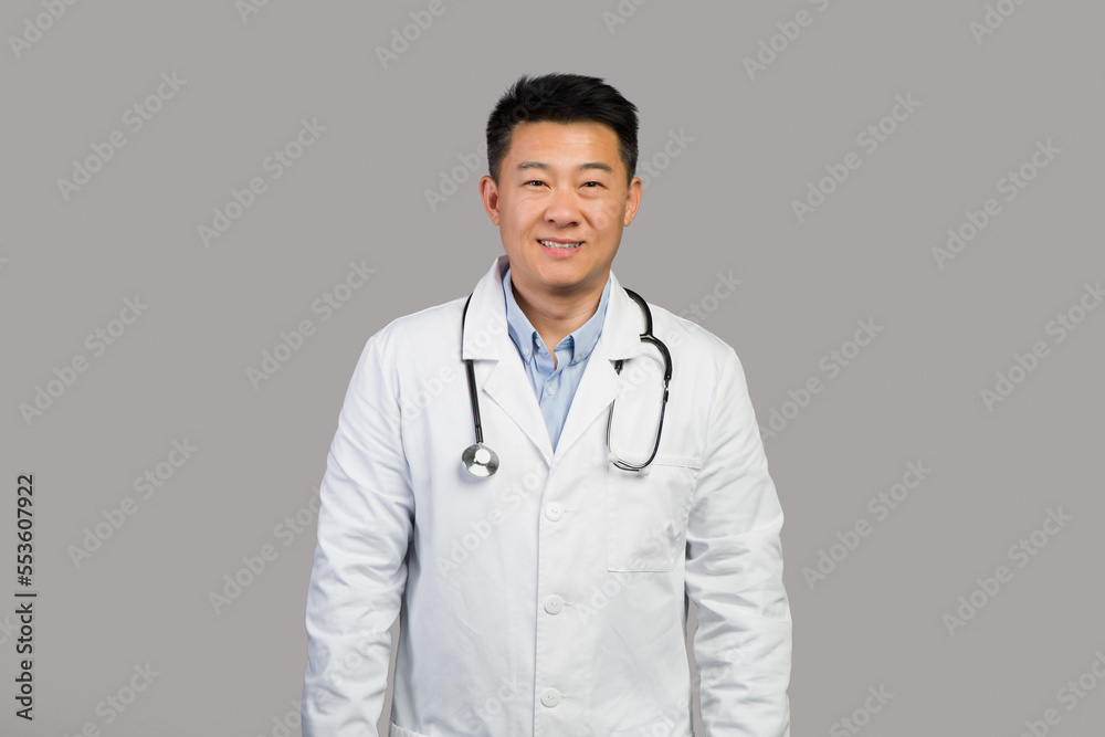 Smiling confident handsome mature chinese man therapist in white coat with stethoscope Smiling confident handsome mature chinese man therapist in white coat with stethoscope