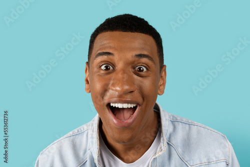 Cheerful funny young african american man with open mouth scream, look at camera