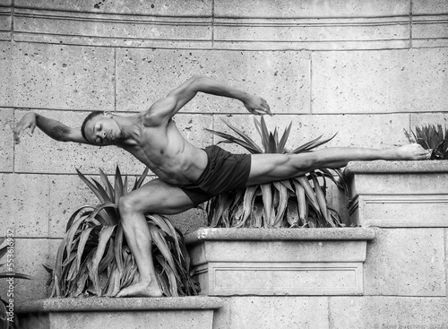 Male dancer posing outside against plants