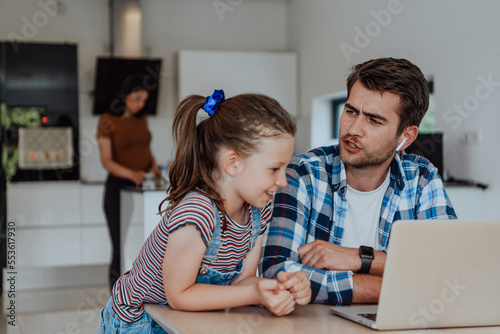 Father and daughter in modern house talking together on laptop with their family during holidays. The life of a modern family