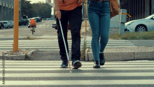 young smiling woman helps his blind friend to cross the street