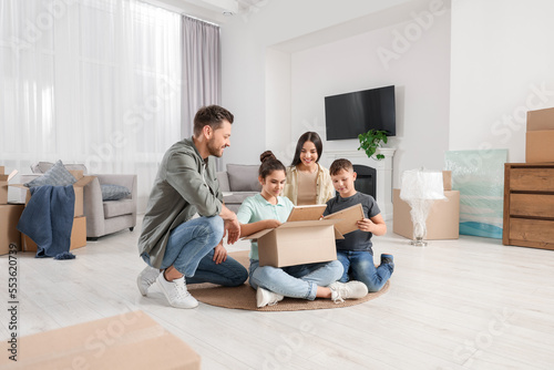 Happy family settling into new house and unpacking boxes on floor. Moving day