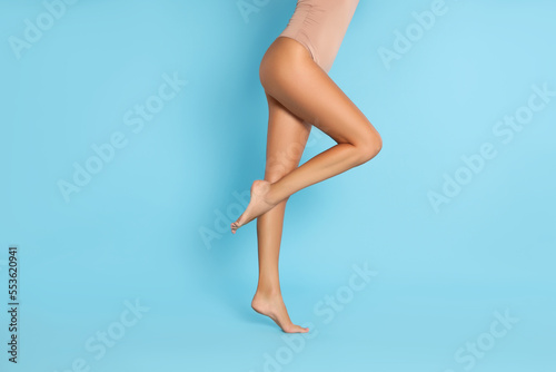 Woman with beautiful long legs on light blue background, closeup