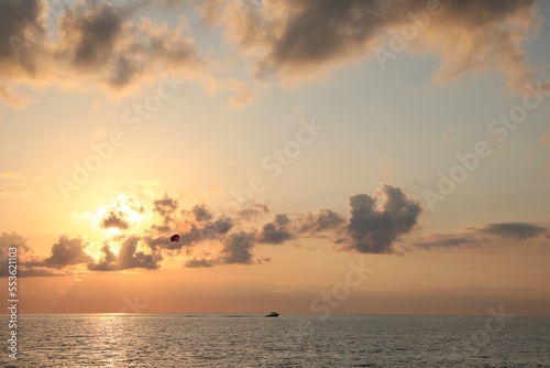 Picturesque view of beautiful sea and people parasailing at sunset