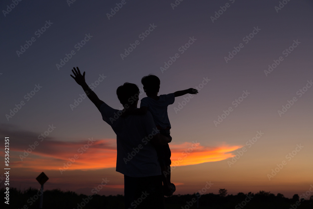 Father and son playing in the park at the sunset time. People having fun on the field.