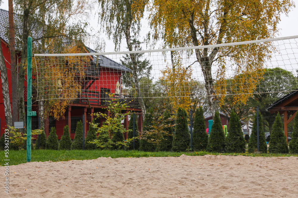 Sand volleyball court with net near trees and buildings Sand volleyball court with net near trees and buildings