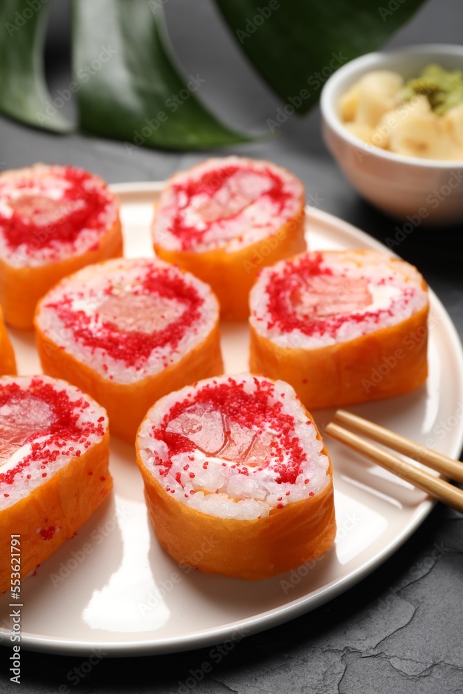 Delicious sushi rolls with salmon and tobiko on grey textured table, closeup Delicious sushi rolls with salmon and tobiko on grey textured table, closeup