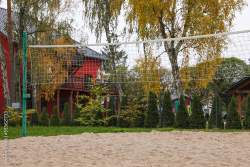 Sand volleyball court with net near trees and buildings