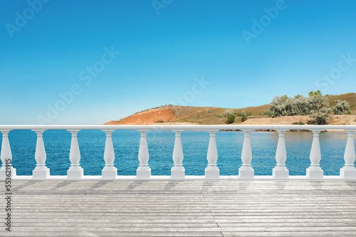 Outdoor wooden terrace revealing picturesque view on sea under blue sky
