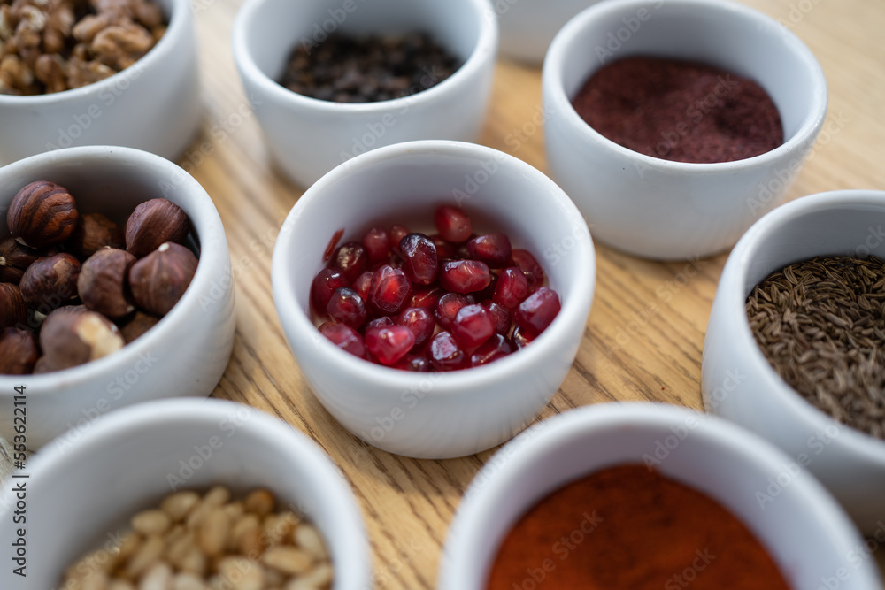 set of spices on wooden background, paprika, pomegranate, pine nut, hazelnut set of spices on wooden background, paprika, pomegranate, pine nut, hazelnut