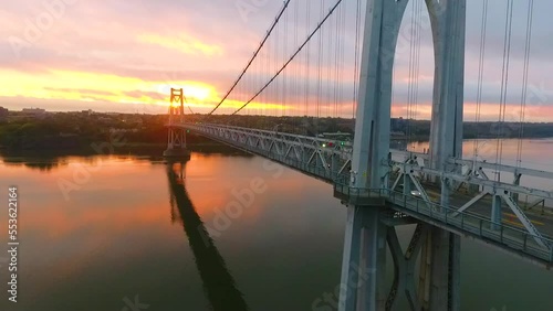 Aerial low to high at pink and golden sunrise light behind stunning American bridge on Hudson River