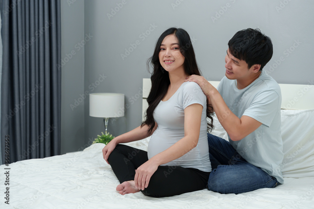 husband massaging shoulders of his pregnant wife on bed. she suffering from back pain