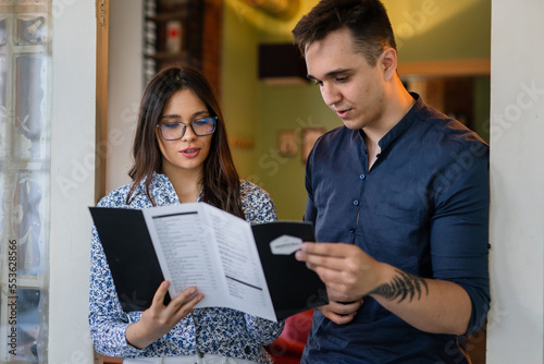 Young couple man and woman at cafe or restaurant checking menu
