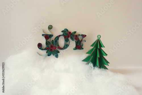 The Word Joy Made from Red and Green Paper Tape, Wood Cutout Christmas Tree, Snow, White Background photo