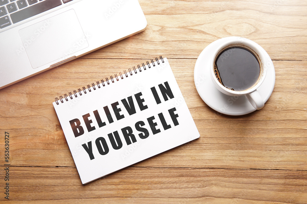 believe yourself, motivational and inspirational words in notebook on table with laptop and cup of coffee.
