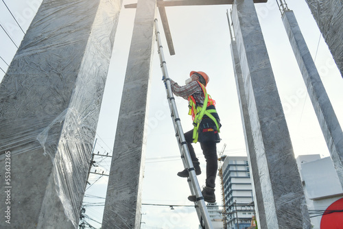 Side view of worker engineer in safety helmet climbing the ladder to get to the top . worker engineer metal roofing work for roof.