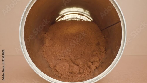 Instant bitter coffee powder with lumps in cylindrical aluminium tin package lying on side in beige studio room macro forward motion photo