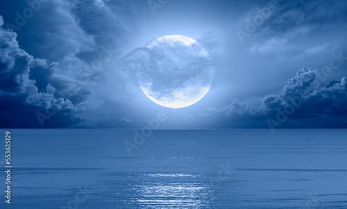 Night sky with blue moon in the clouds over the calm blue sea "Elements of this image furnished by NASA © muratart