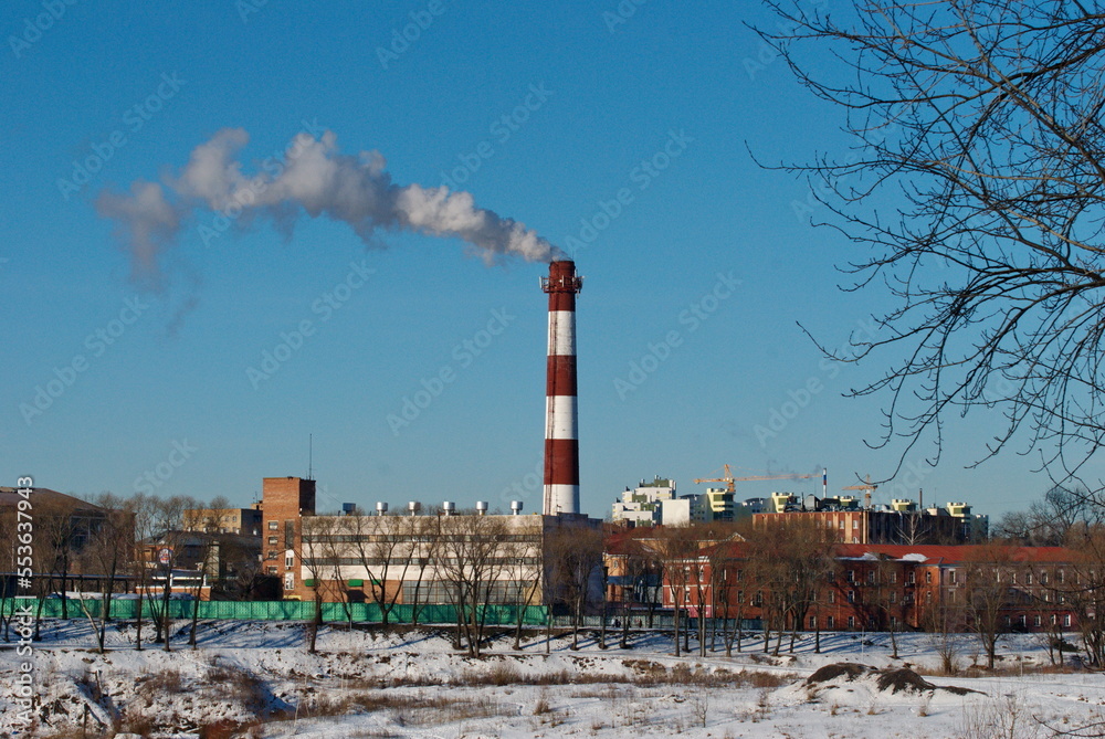 The smoking chimney of the factory on a sunny day. Moscow region. Russia