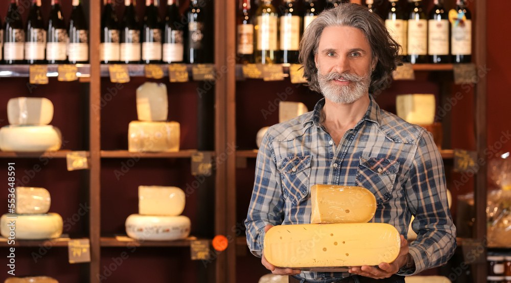 Senior business owner with tasty cheese in his store Senior business owner with tasty cheese in his store