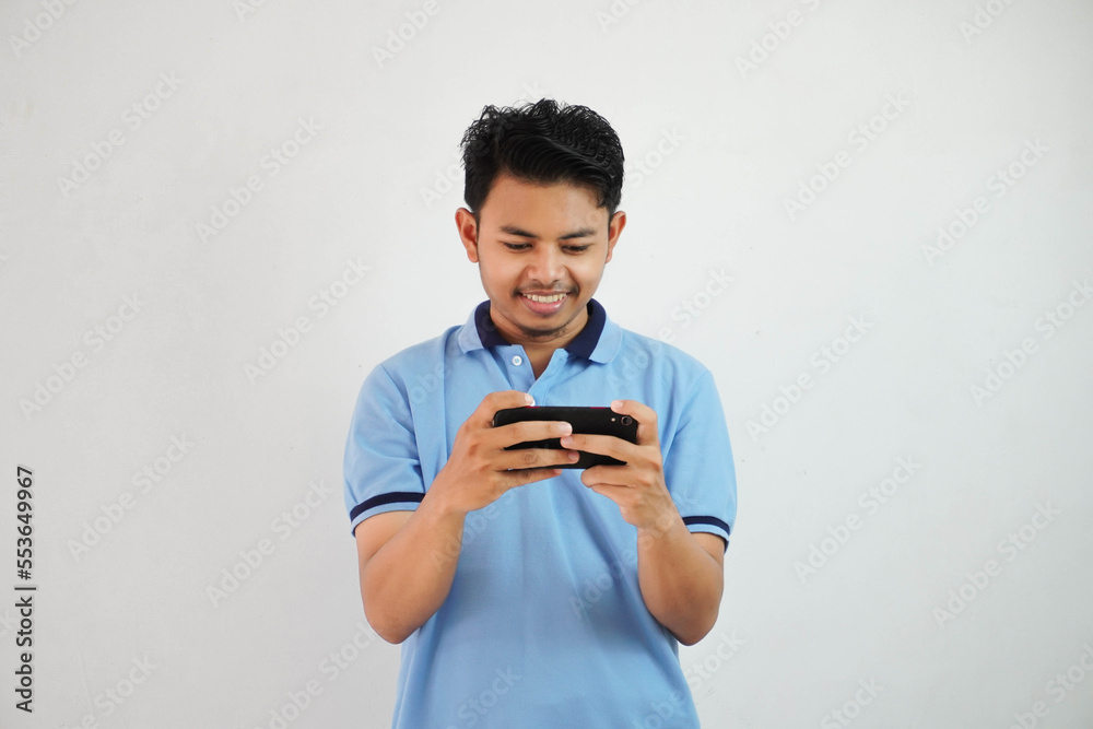 smiling or happy portrait young asian man playing game with smartphone isolated on white background smiling or happy portrait young asian man playing game with smartphone isolated on white background