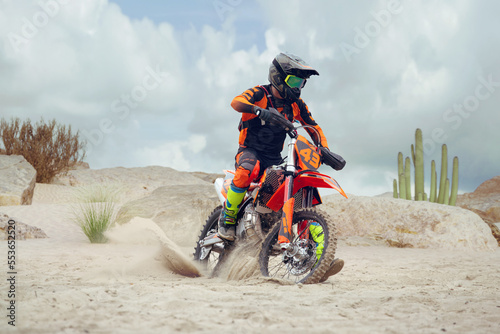 Young man practice riding dirt motorcycle. Splashing sand photo