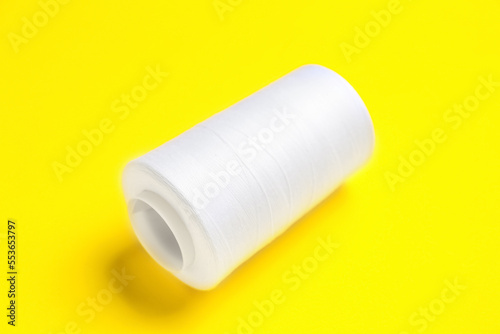 Tailoring and sewing craft, white thread spool for textile industry and fashion design on a bright yellow background