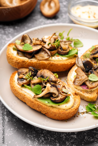 Plate of tasty toasts with cream cheese and mushrooms on grunge background, closeup